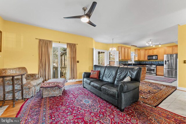 living room with sink, rail lighting, and ceiling fan with notable chandelier