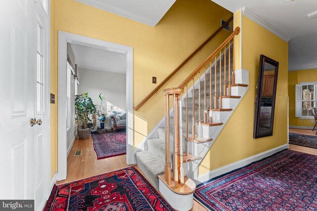 staircase with hardwood / wood-style flooring and ornamental molding