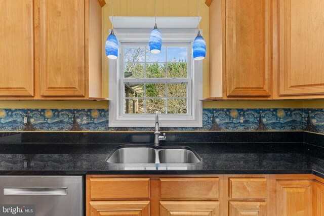 kitchen with decorative light fixtures, dishwasher, sink, and dark stone countertops