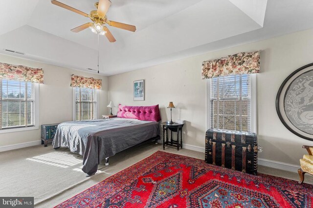 carpeted bedroom with ceiling fan and a raised ceiling