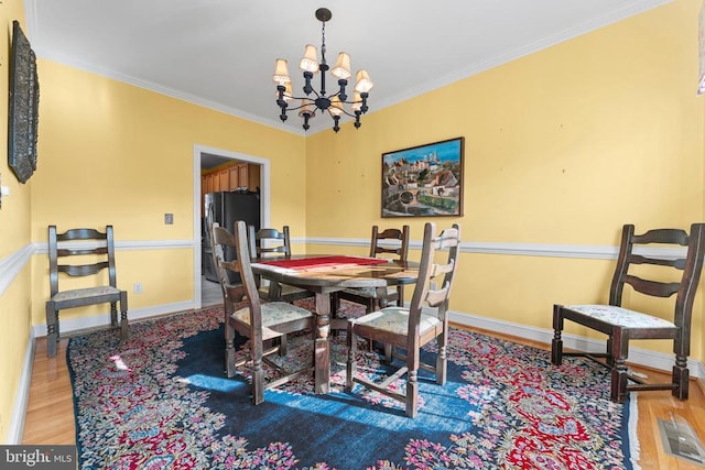 dining space with hardwood / wood-style floors, ornamental molding, and a chandelier