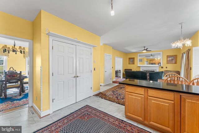 kitchen featuring track lighting, ceiling fan with notable chandelier, and hanging light fixtures