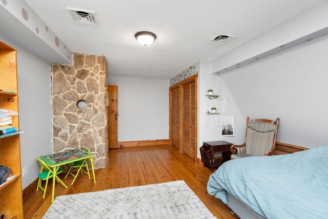 bedroom with baseboards, a closet, visible vents, and wood finished floors