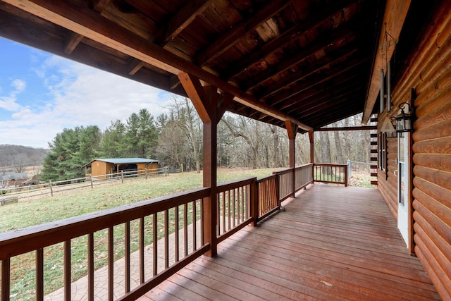 wooden deck with an outbuilding, fence, and a lawn