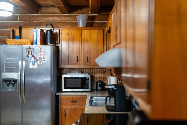 kitchen with stainless steel appliances, brown cabinetry, and beamed ceiling