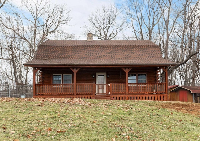 log-style house featuring covered porch, a chimney, log exterior, and a front lawn