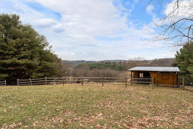 view of yard with a rural view, an outdoor structure, a forest view, and an exterior structure