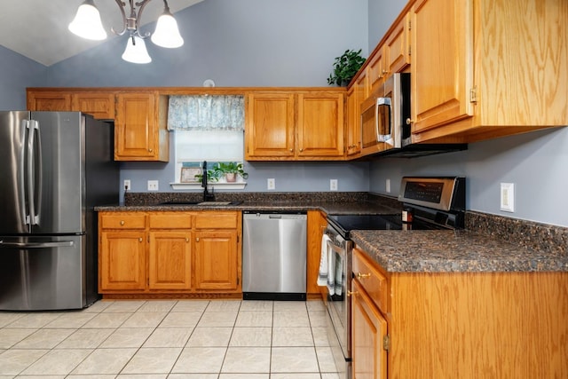 88 Ashleigh Dr, Waynesboro, VA 22980 - kitchen featuring appliances with stainless steel finishes, a sink, light tile patterned floors, brown cabinetry, and vaulted ceiling