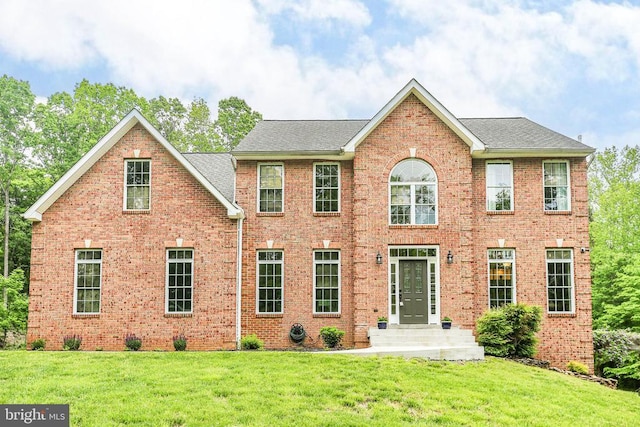 - view of front facade featuring brick siding, a front lawn, and a shingled roof