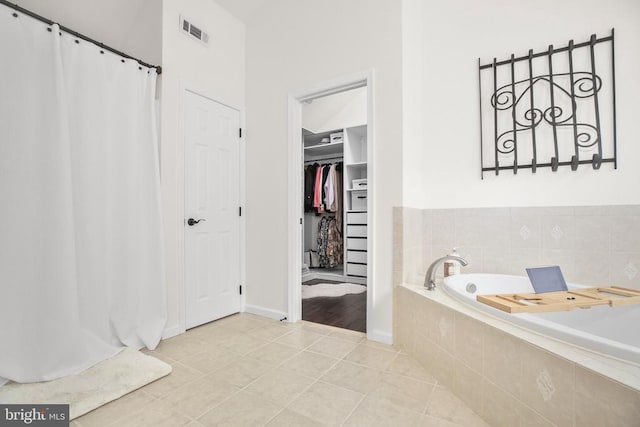  - bathroom with tile patterned flooring, a bath, a walk in closet, baseboards, and curtained shower