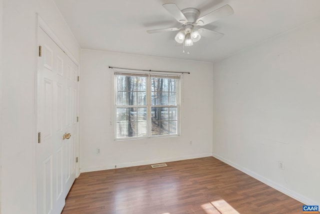 unfurnished bedroom featuring a ceiling fan, visible vents, wood finished floors, and baseboards