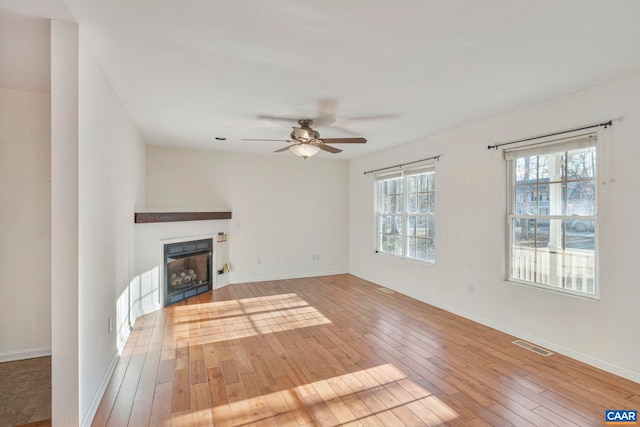 unfurnished living room featuring a fireplace, a ceiling fan, visible vents, and light wood-style floors
