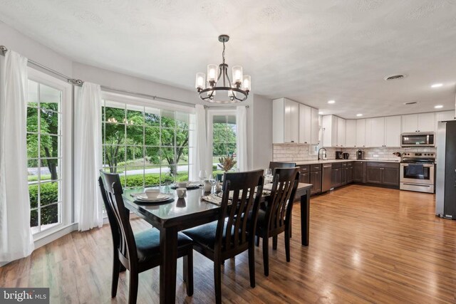 dining room featuring a chandelier, light wood-style flooring, and recessed lighting