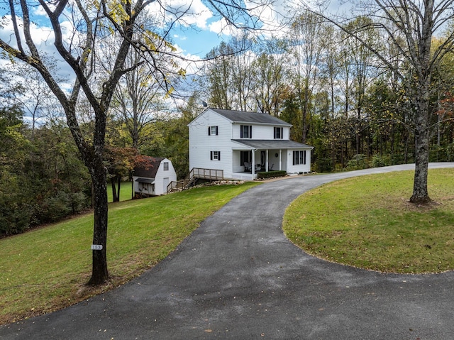 view of front of house with a porch, a shed, and a front lawn