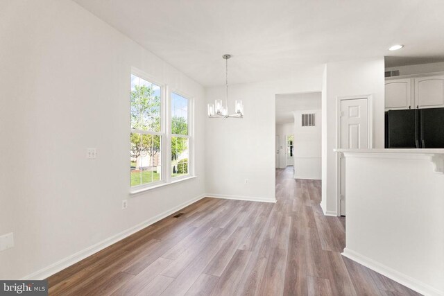  - unfurnished dining area featuring a chandelier, light wood-style flooring, baseboards, and recessed lighting