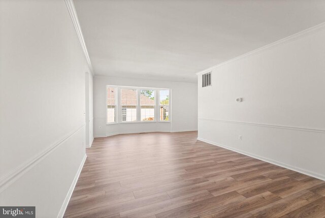  - spare room with ornamental molding, wood finished floors, and baseboards