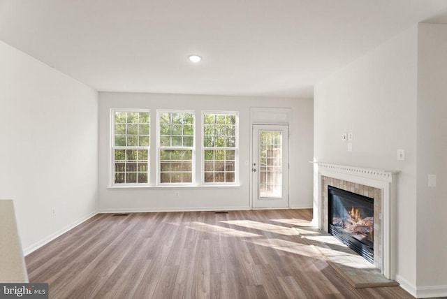  - unfurnished living room featuring wood finished floors, a tile fireplace, baseboards, and recessed lighting