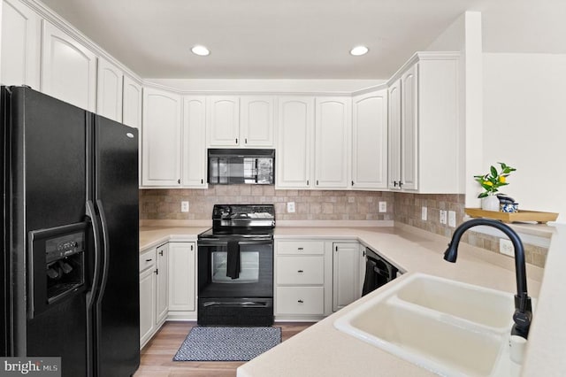  - kitchen featuring black appliances, a sink, white cabinetry, light countertops, and recessed lighting