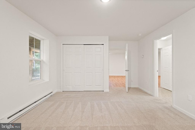  - unfurnished bedroom with a baseboard heating unit, light colored carpet, baseboards, and a closet