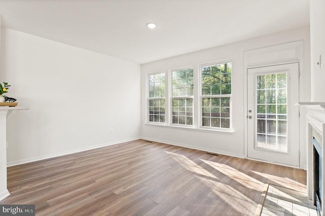  - unfurnished living room featuring a high end fireplace, wood finished floors, baseboards, and recessed lighting