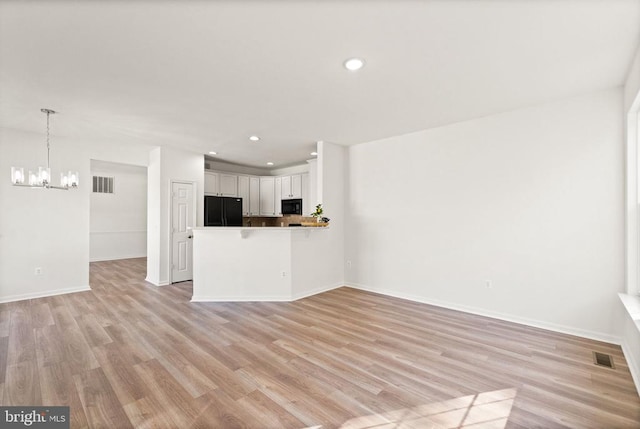  - unfurnished living room featuring a chandelier, light wood-style floors, baseboards, and recessed lighting