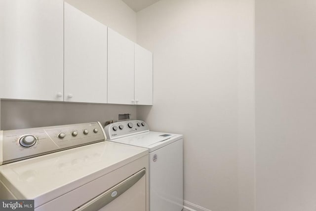  - clothes washing area with washing machine and clothes dryer, cabinet space, and baseboards