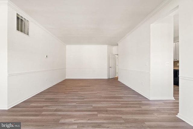  - spare room with light wood-type flooring, ornamental molding, and baseboards