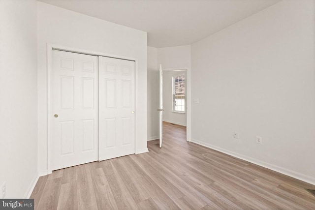  - unfurnished bedroom featuring light wood-style floors, baseboards, and a closet