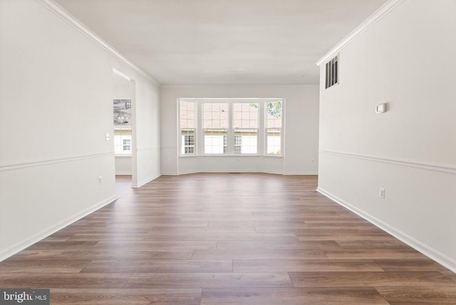  - empty room featuring healthy amount of natural light, ornamental molding, wood finished floors, and baseboards