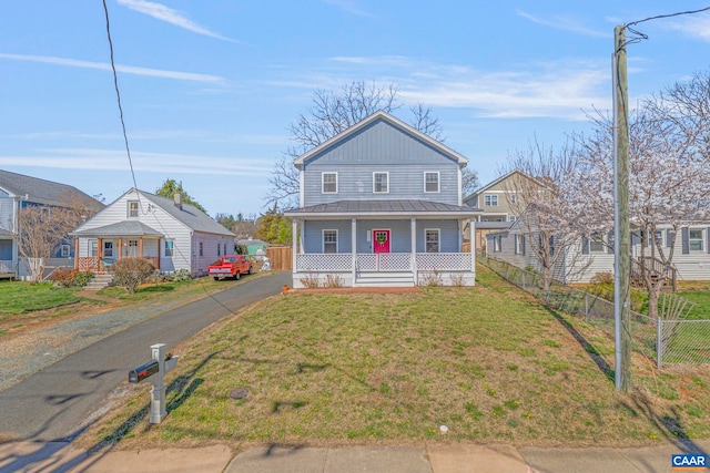 view of front of house featuring a porch, fence, metal roof, a front lawn, and a standing seam roof