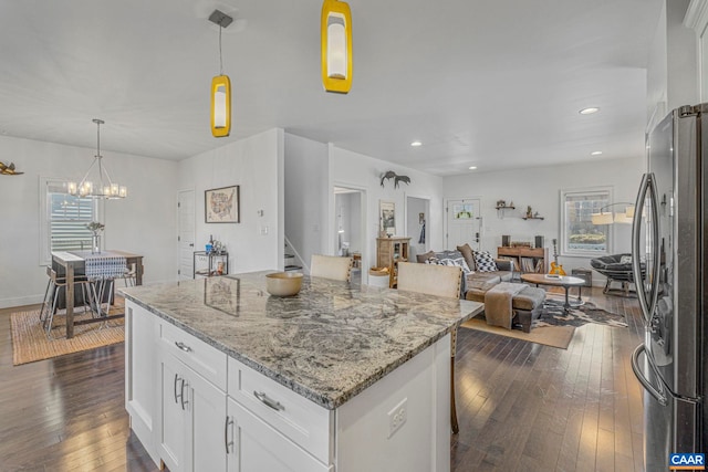 kitchen with freestanding refrigerator, white cabinets, dark wood-style flooring, light stone countertops, and a kitchen island
