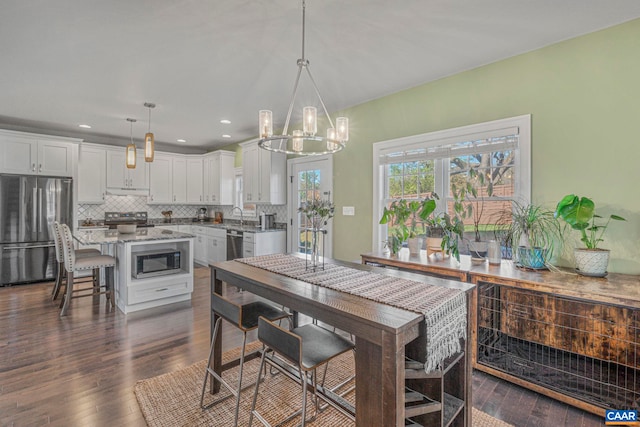 dining space with a chandelier, dark wood-type flooring, and recessed lighting