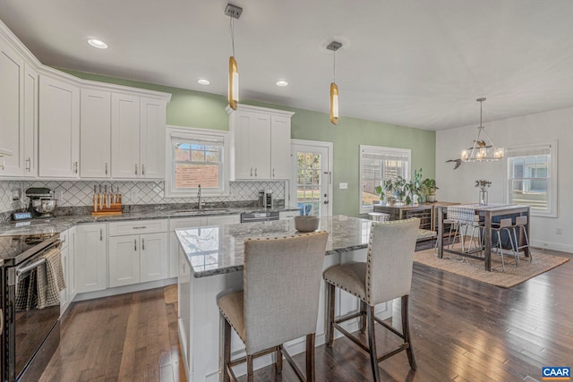 kitchen featuring dark wood-style flooring, electric range oven, a sink, white cabinets, and tasteful backsplash