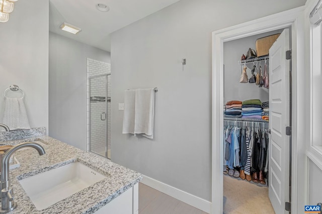 full bath featuring a stall shower, recessed lighting, baseboards, vanity, and a spacious closet
