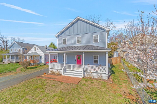 view of front of home featuring metal roof, board and batten siding, a front yard, a porch, and a standing seam roof