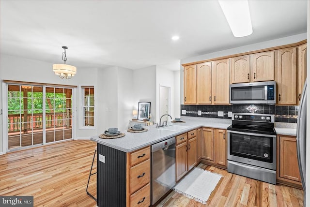 7924 Gold Leaf Cir, Spotsylvania, VA 22551 - kitchen featuring appliances with stainless steel finishes, tasteful backsplash, a peninsula, light wood-style flooring, and pendant lighting