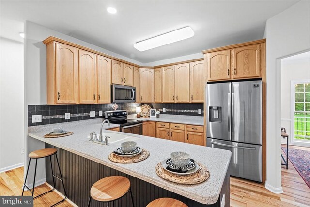 7924 Gold Leaf Cir, Spotsylvania, VA 22551 - kitchen featuring appliances with stainless steel finishes, light brown cabinets, light wood-style flooring, light countertops, and a peninsula