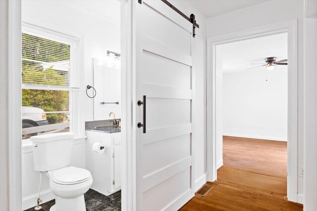 bathroom featuring toilet, plenty of natural light, wood finished floors, and baseboards
