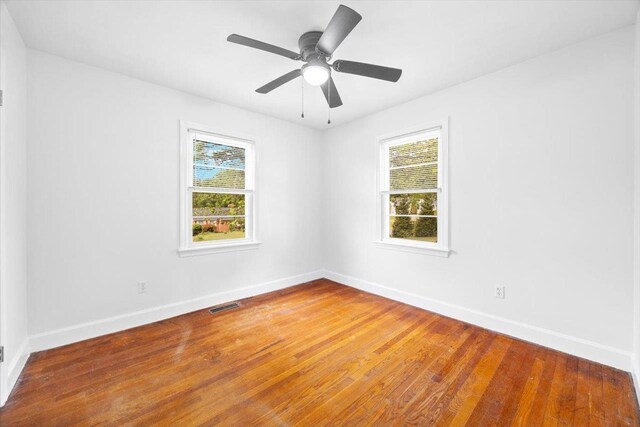 unfurnished room featuring plenty of natural light, baseboards, and wood finished floors