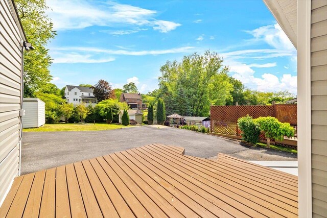 wooden terrace featuring driveway, a patio, a residential view, and fence