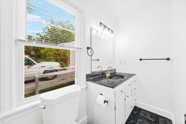 half bath featuring toilet, baseboards, and vanity