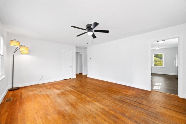 spare room featuring wood finished floors, ceiling fan, and baseboards