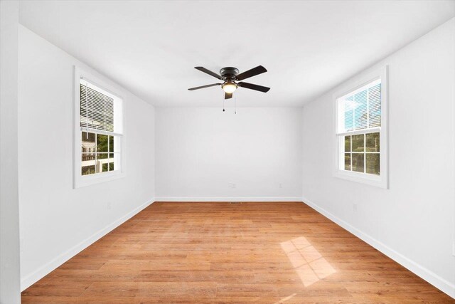 empty room with healthy amount of natural light, light wood-type flooring, ceiling fan, and baseboards