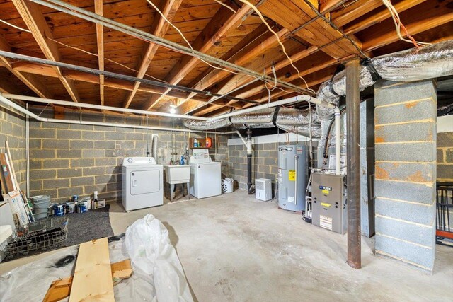 unfinished below grade area featuring water heater, separate washer and dryer, a sink, and concrete block wall