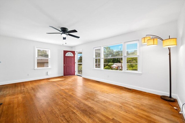 unfurnished living room featuring baseboards, a ceiling fan, and wood finished floors