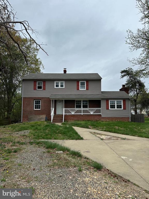 view of front of home featuring brick siding, a porch, and a chimney