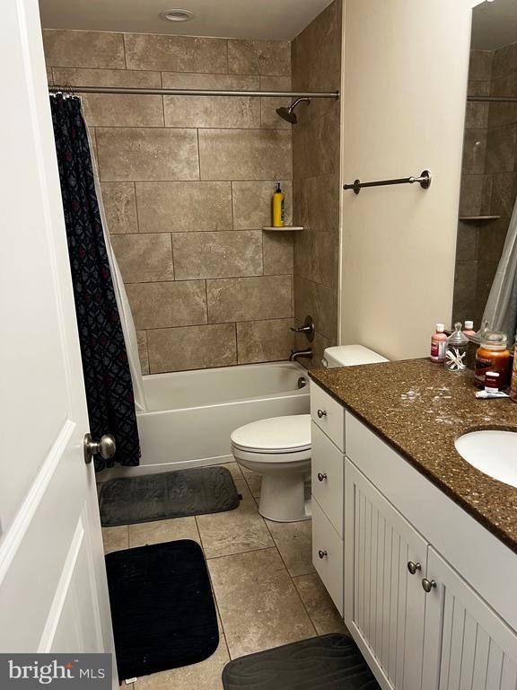 bathroom featuring vanity, tile patterned flooring, toilet, and shower / bathtub combination with curtain