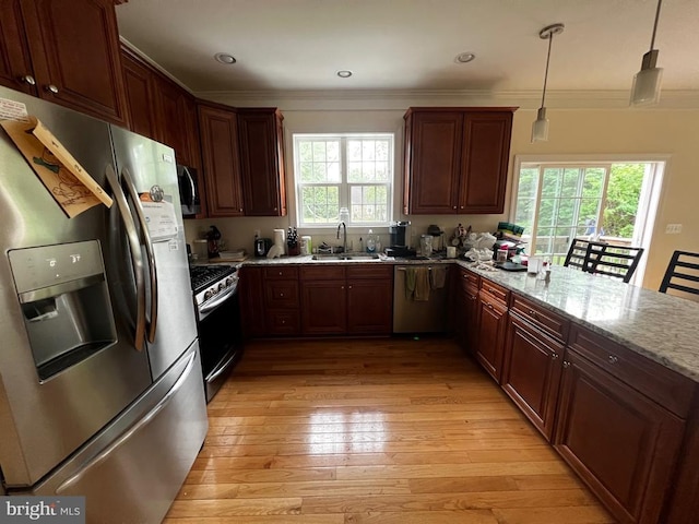 kitchen featuring crown molding, appliances with stainless steel finishes, light wood-type flooring, a sink, and a peninsula