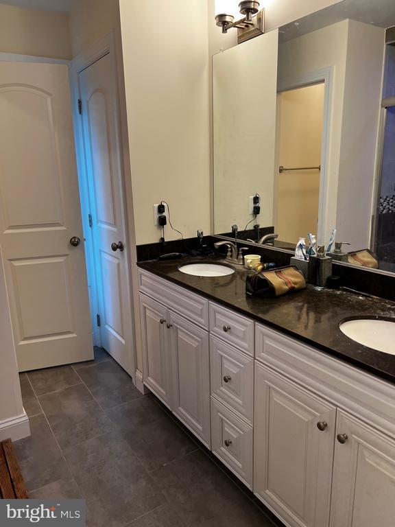 full bathroom featuring double vanity, a sink, and tile patterned flooring
