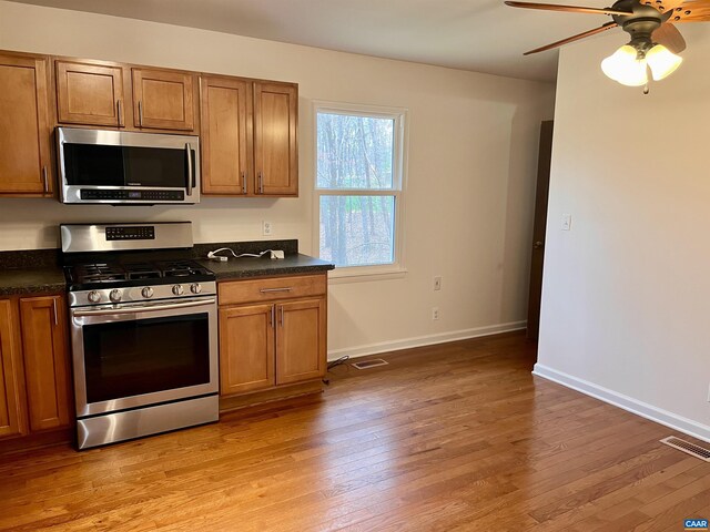 4646 Woods Edge Rd, Troy, VA 22974 - kitchen featuring stainless steel appliances, brown cabinets, dark countertops, ceiling fan, and light wood-style floors